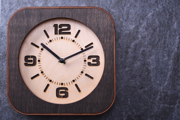木製の背景に手で作られた木製の時計。閉じる。テキストのための場所。
