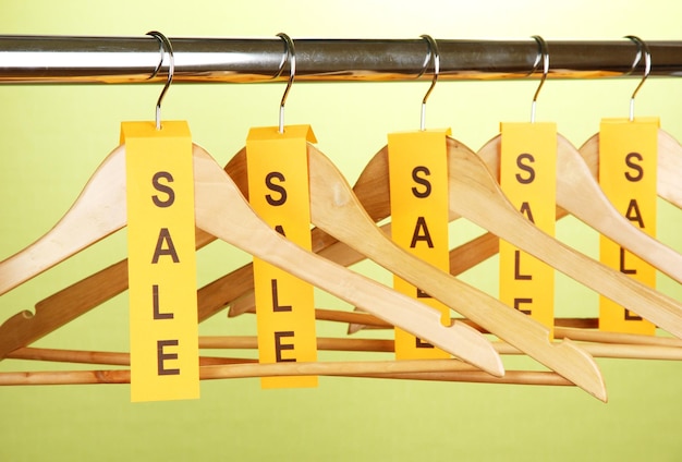 Wooden clothes hangers as sale symbol on green background