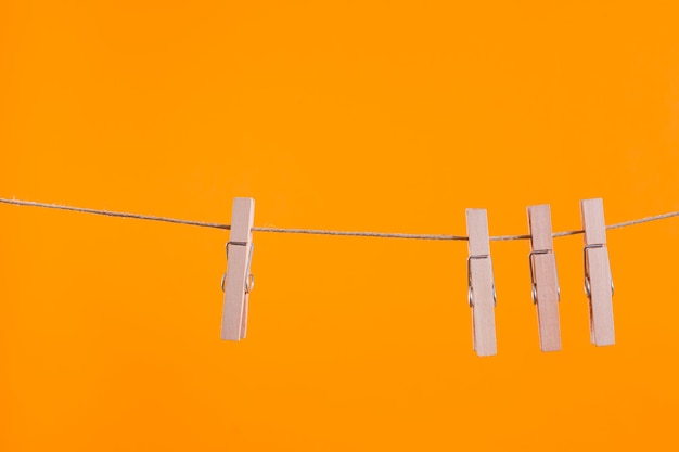 Wooden clothespins hanging on a clothesline rope over orange wall Team work leadership difference concept