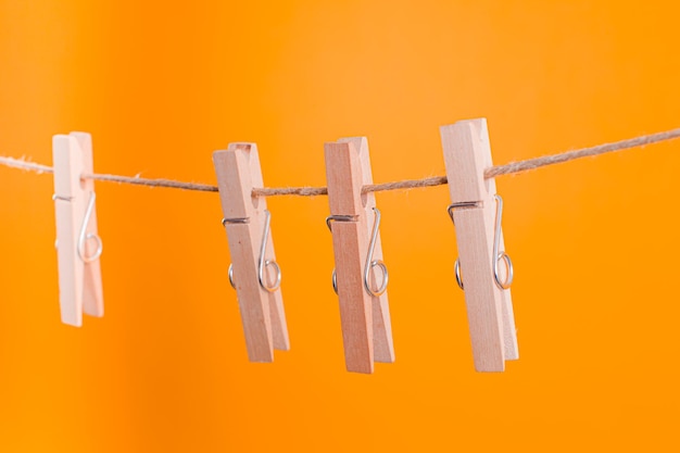 Wooden clothespins hanging on a rope over yellow background Reusable objects for home using Zero waste concept