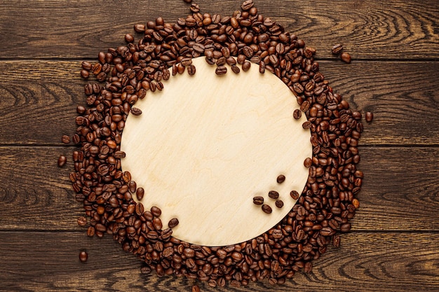 Wooden coffee coaster on wood table background coffee beans scattered in circle with blank space for