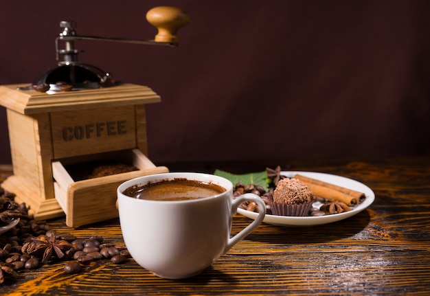 Macinacaffè in legno con tazza bianca e dolcetto