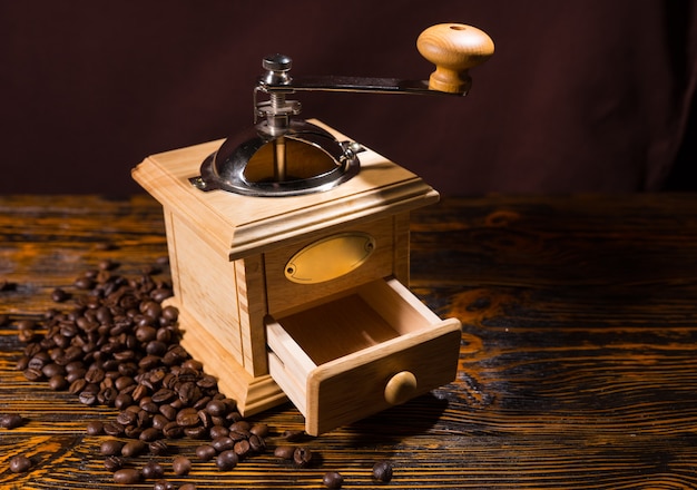 Wooden coffee grinder with scattered beans