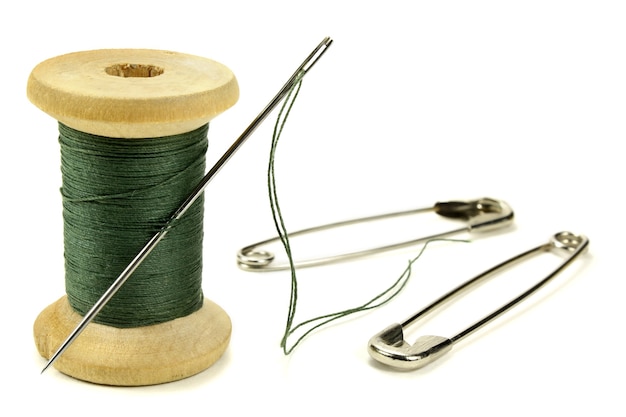 Wooden coil with threads needle and safety pin for sewing on white