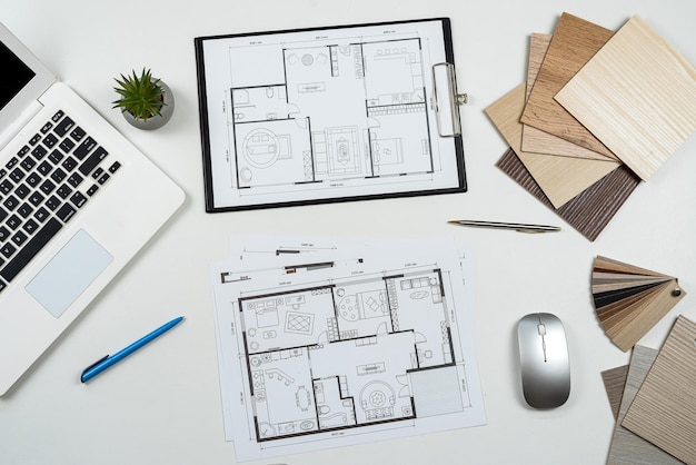 Photo wooden color samples and blueprints of project with laptop for interior renovation in workplace