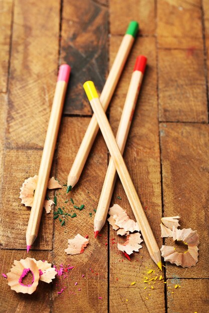 Wooden colorful pencils with sharpening shavings on wooden table