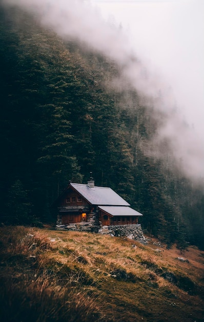 Photo wooden cottage in the forest in a foggy misty morning