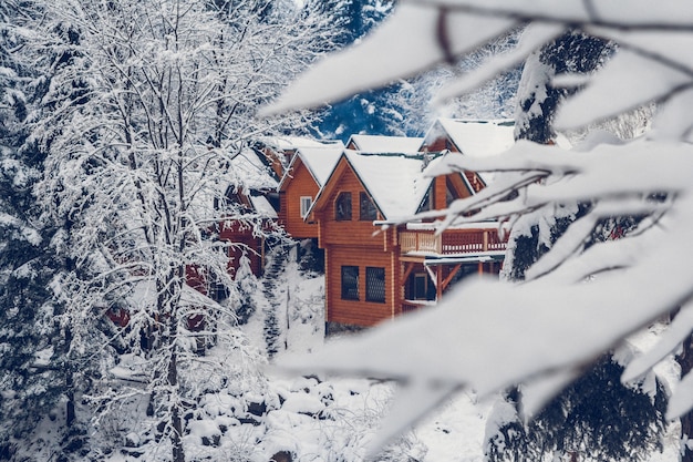 Wooden cottage holiday house in mountain holiday resort covered\
with fresh snow in winter.