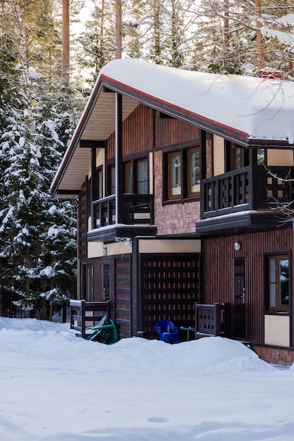 Wooden cottage near the pine forest, covered in snow