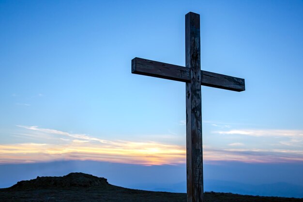 Wooden cross on a background of sunrise in the mountains