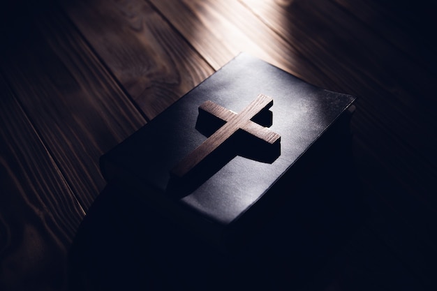 Photo wooden cross on holy bible on wooden background