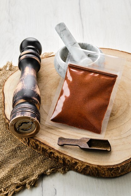 Wooden cross section with chilli pepper in plastic package and stone mortar and mill