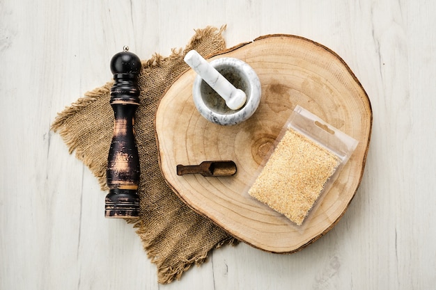 Wooden cross section with garlic in plastic package and stone mortar and mill