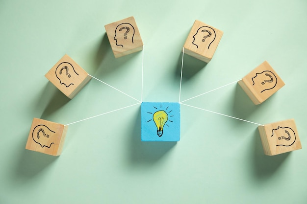 Wooden cube blocks with human head symbols with question mark\
and light bulb symbol