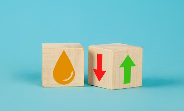 Wooden cube change up arrow and down arrow and oil symbol on blue background oil with arrow up falli