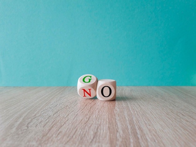 Wooden cube flipping for change between go and no beautiful blue background concept copy space