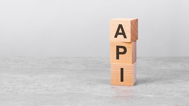 Foto cubo di legno su un tavolo bianco con testo api concetto di business investimento finanziario economia copia spazio a sinistra per il design sfondo grigio api abbreviazione di interfaccia di programmazione dell'applicazione