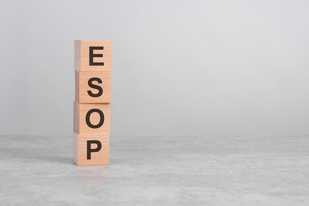 Wooden cube on a white table with text ESOP concept of business financial investment economy copy space on right for you design gray background ESOP  short for employee stock ownership plan