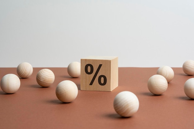 Wooden cube with a question mark surrounded by wooden balls on a black table background
