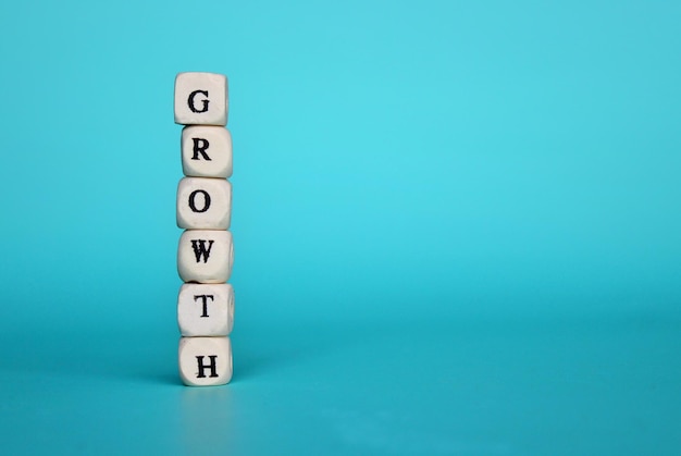 Wooden cube with text GROWTH on green background with copy space for text