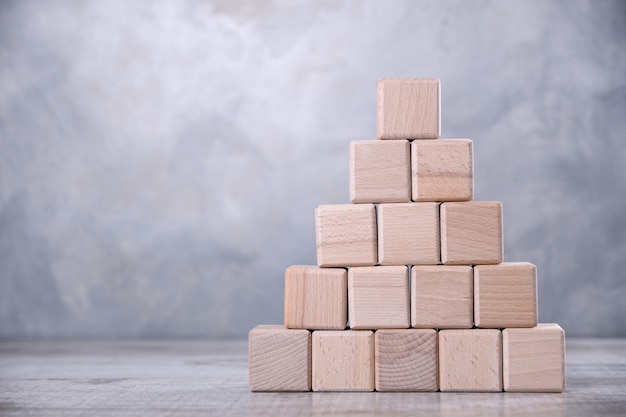 Wooden cubes are stacked in the form of stairs on a wooden table. The concept of development, growth,the boss, the best.