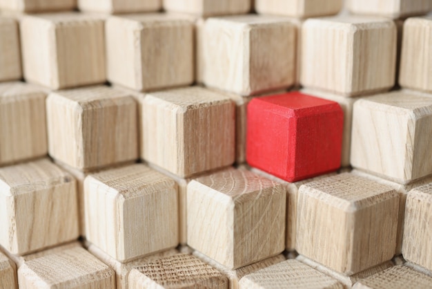 Wooden cubes of beige color in middle of red stands in pyramid individual approach in business