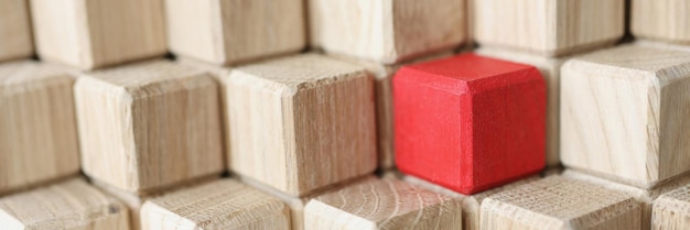 Wooden cubes of beige color in middle of red stands in pyramid individual approach in business