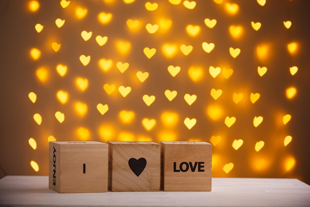 Wooden cubes I Love You on a blurred background of hearts