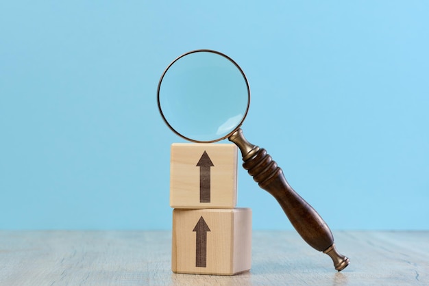 Photo wooden cubes and magnifying glass on blue background