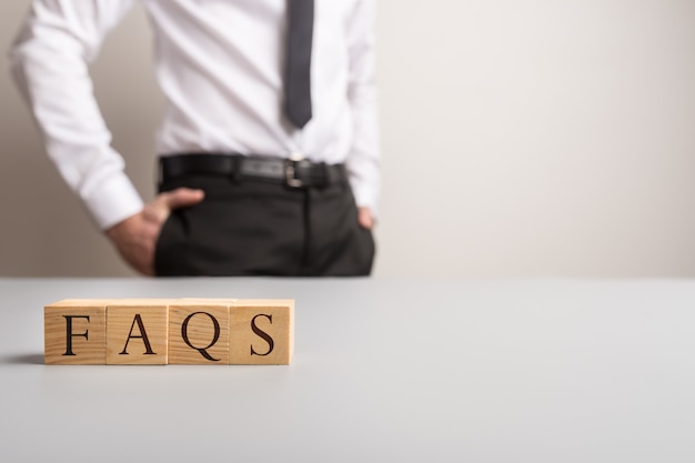 Wooden cubes spelling FAQS with businessman standing