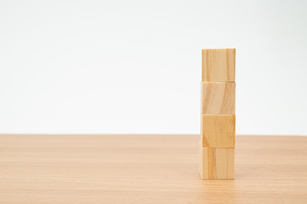 Wooden cubes stacked up on a wooden table with a white background