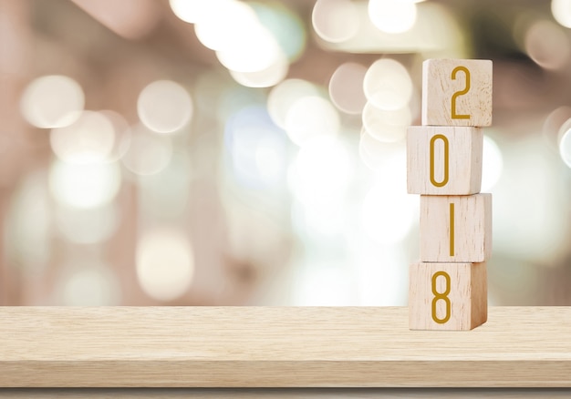 Wooden cubes with 2018 on perspective wood over blur bokeh background with copy space for text, new year template