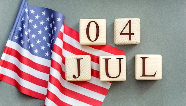 Wooden cubes with date of 4 july and american flag on grey background