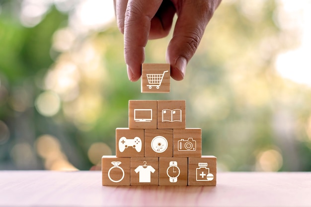 Wooden cubes with different icons on them, and the top one is being picked up by a hand.