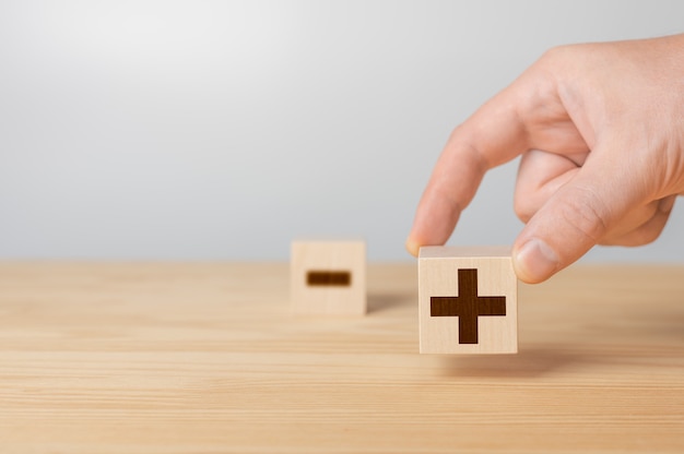 Wooden cubes with the image pros versus cons Plus or minus Businessman holds a cubes with plus icon