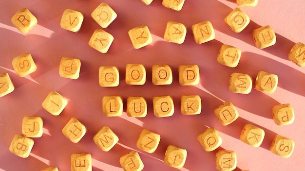 Photo wooden cubes with the inscription good luck on a pink background selective focus