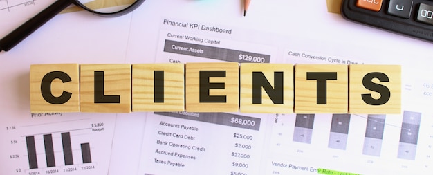 Wooden cubes with letters on the table in the office. Text CLIENTS. Financial concept.