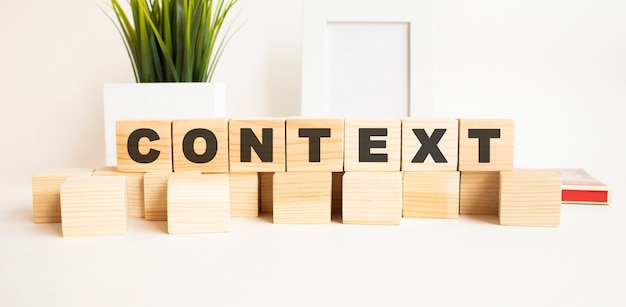 Wooden cubes with letters on a white table. White background with photo frame, house plant.