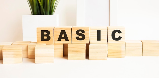 Wooden cubes with letters on a white table The word is BASIC White background