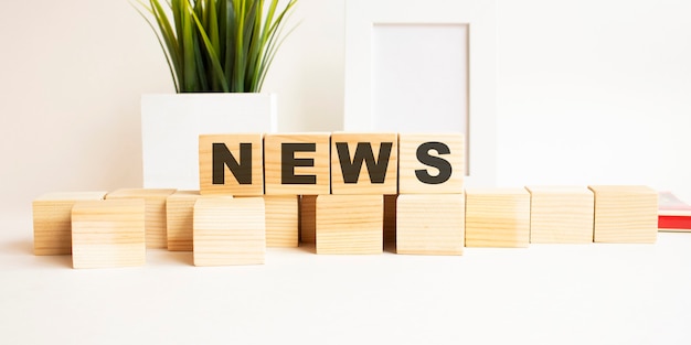 Wooden cubes with letters on a white table The word is NEWS