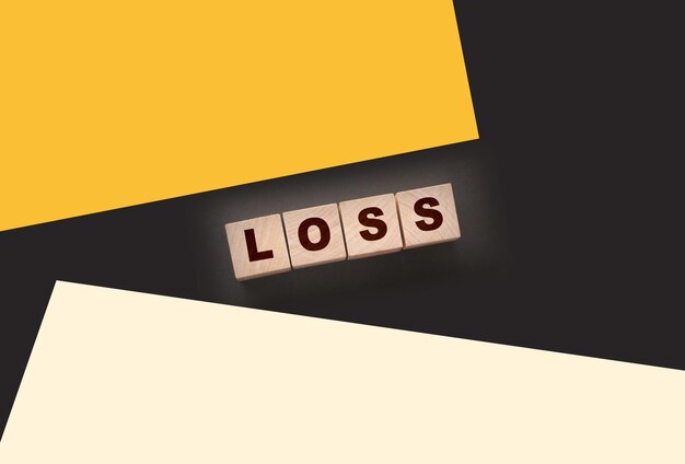 Деревянные кубики со словом LOSS на черном столе Концепция бизнеса финансовых потерь