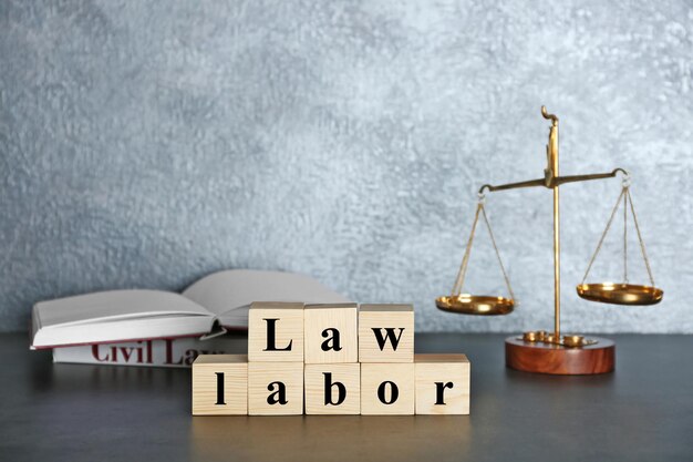 Wooden cubes with phrase LAW LABOR and scales on a table