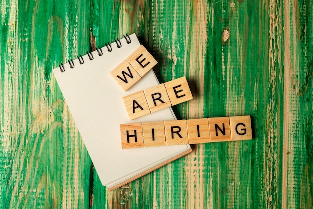 Wooden cubes with We Are Hiring letters and an empty notebook