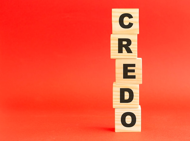 Wooden cubes with word CREDO.  Wooden cubes on a red surface. Free space on the left.