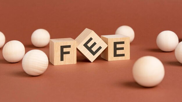 Wooden cubes with word FEE on brown background front view