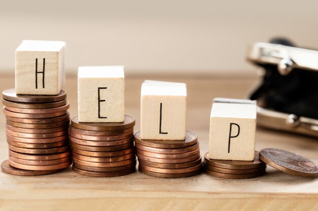 Wooden cubes with the word Help and pile of coins