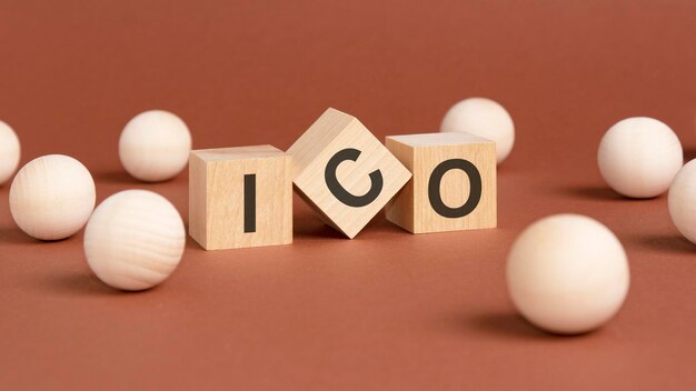 Wooden cubes with word ico on brown background front view