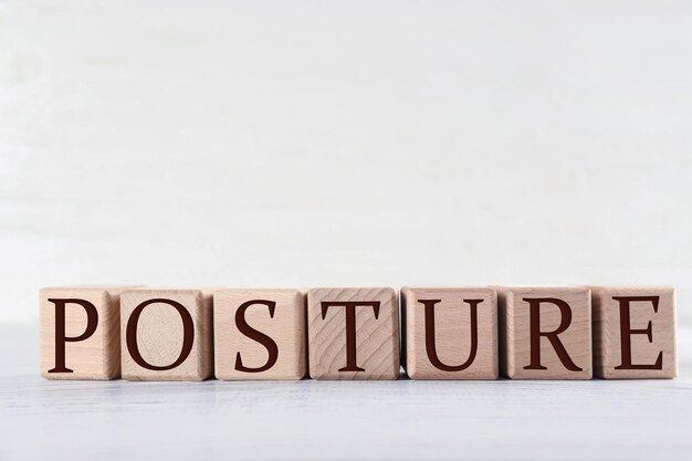 Wooden cubes with word POSTURE on table against light background