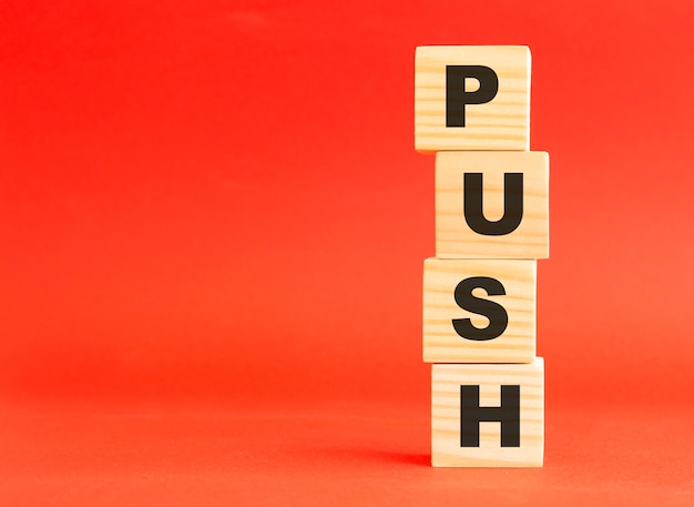 Wooden cubes with word PUSH. For your design and concept. Wooden cubes on a red background. Free space on the left.