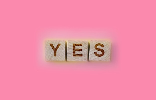 Wooden cubes with word yes on pink table positive answer and\
positive thinking concept